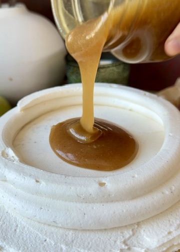 Salted caramel being poured inside a tall vanilla buttercream dam