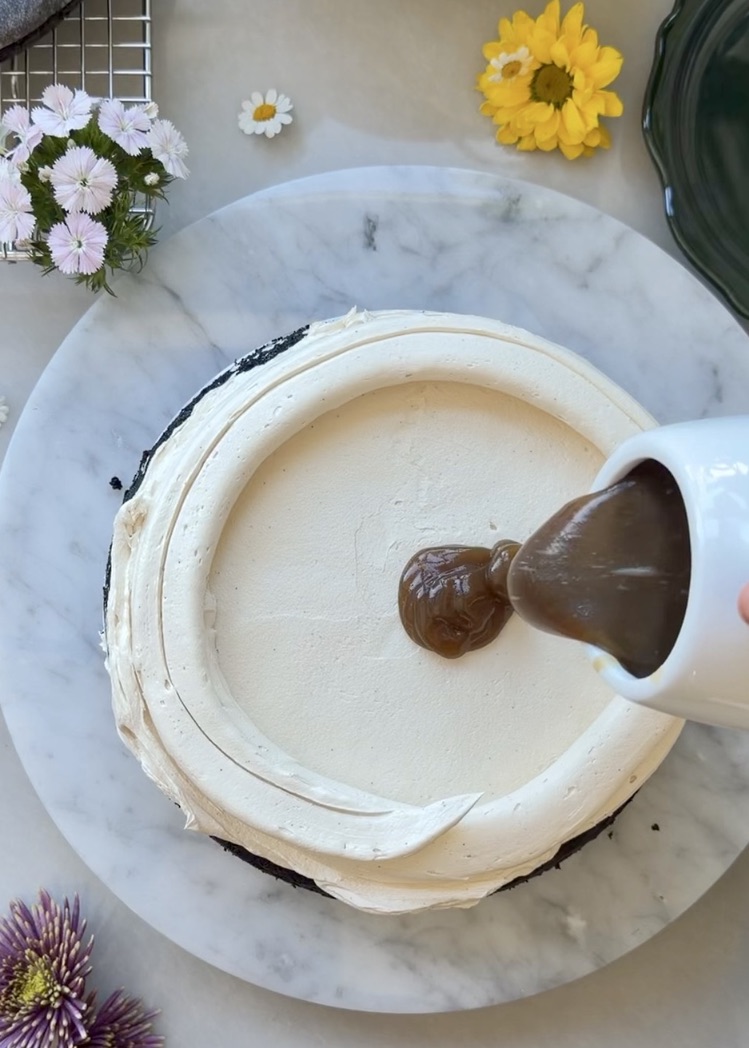 Salted brown sugar caramel being poured inside a vanilla latte buttercream dam