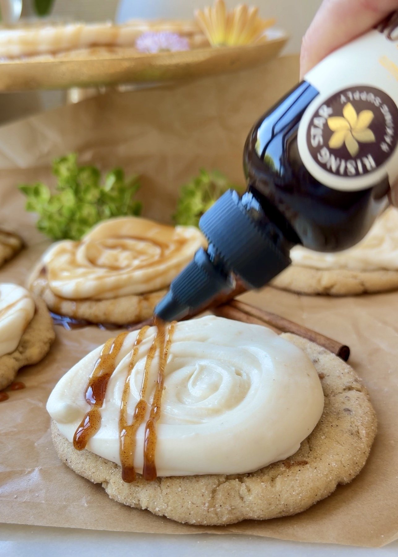 Cinnamon syrup being drizzled over frosted Snickerdoodle Cheesecake Cookies