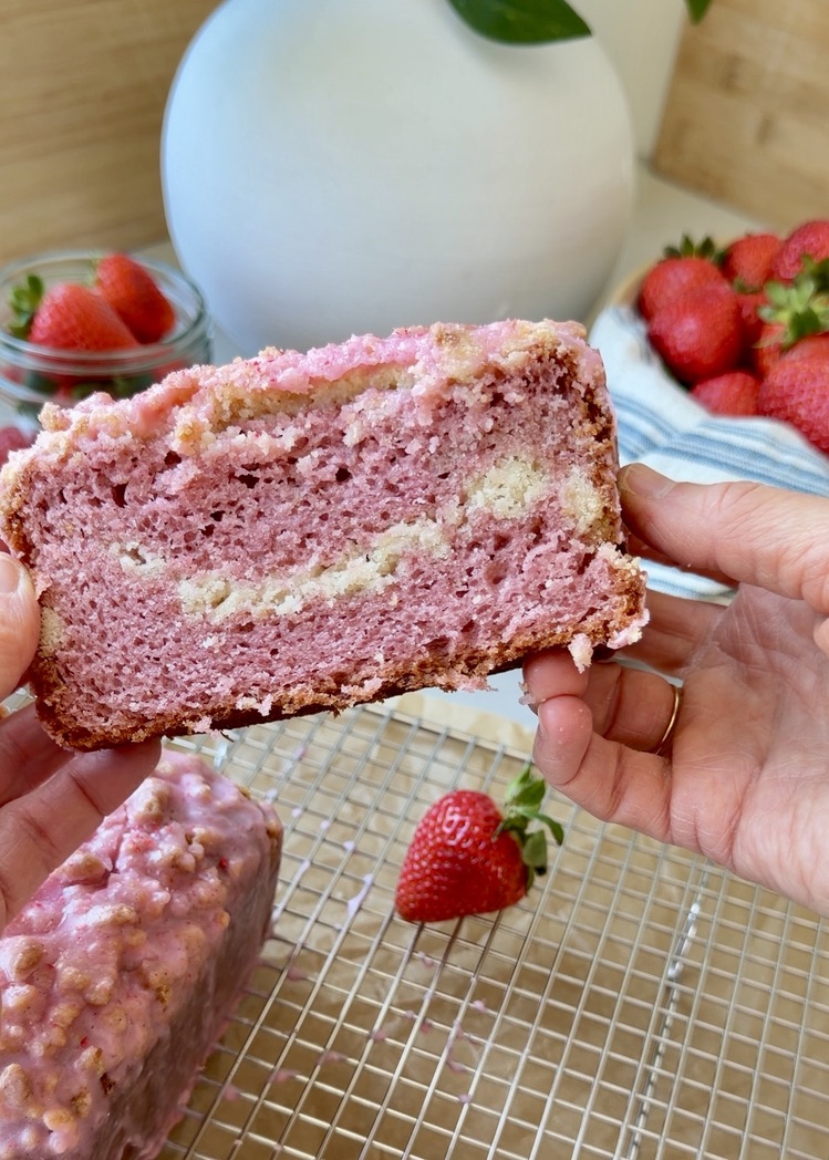 Slice of strawberry old-fashioned donut loaf showing its pink crumb and middle streusel layer