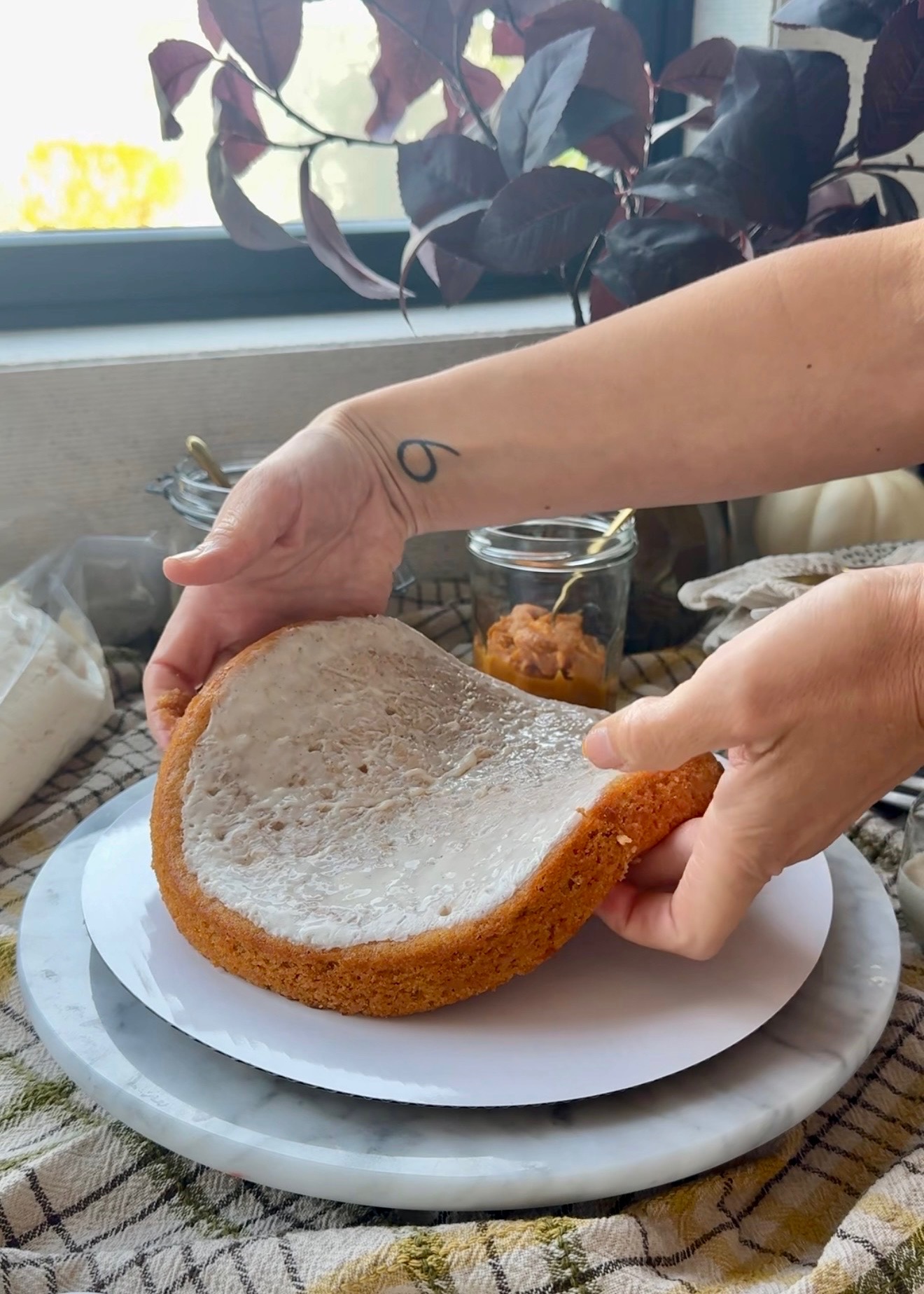 Glaze-soaked sweet potato cake layer being placed on a cake board