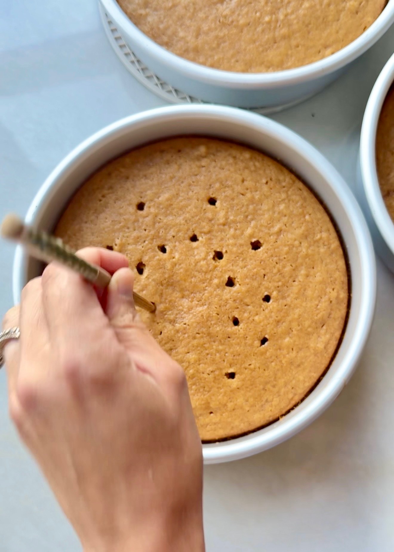 Small holes being poked into warm sweet potato cake layers