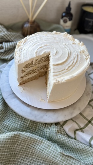 A finished vanilla bean layer cake with a slice removed and soft swirls of buttercream