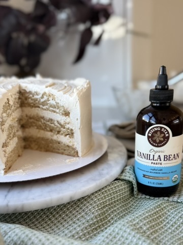 A sliced vanilla layer cake beside a bottle of Rising Star vanilla bean paste