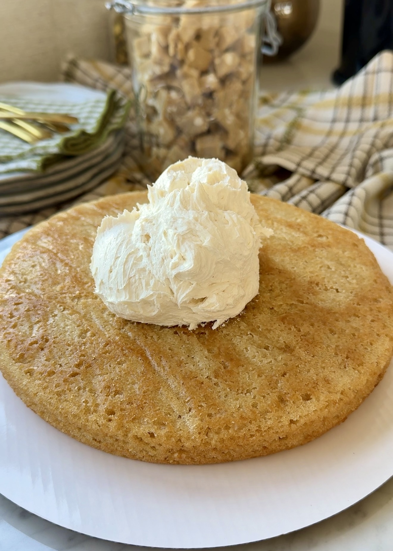 Vanilla bean buttercream placed on a vanilla cake layer with blondie pieces nearby