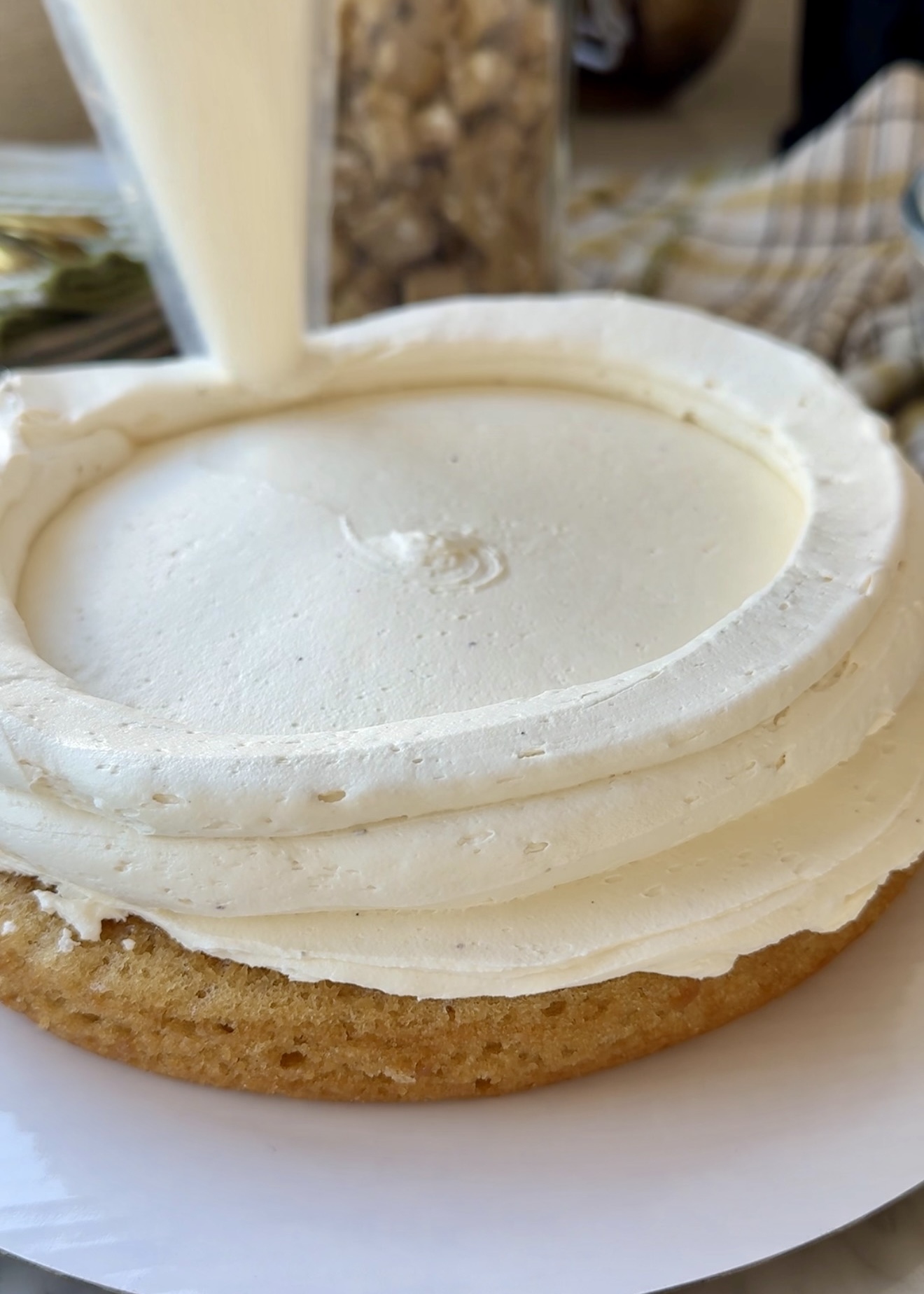 Tall vanilla bean buttercream dam piped around a vanilla cake layer